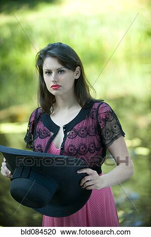 Stock Image - Glamorous woman holding large hat. Fotosearch