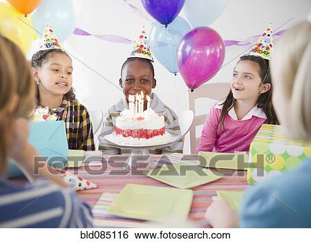 Stock Photograph - Happy boy at birthday party with birthday cake. Fotosearch