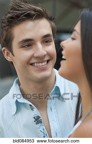 Stock Image - Hispanic man watching laughing girlfriend. Fotosearch