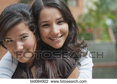 Stock Image - Hispanic sisters hugging. Fotosearch