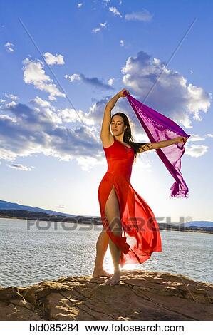 Picture - Hispanic woman dancing near lake. Fotosearch