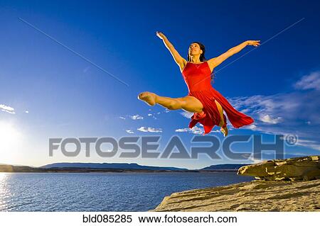 Stock Photography - Hispanic woman dancing near lake. Fotosearch