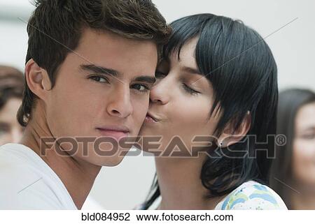Stock Image - Hispanic woman kissing boyfriend. Fotosearch