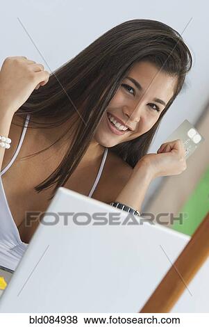 Stock Photo - Hispanic woman shopping online with credit card. Fotosearch