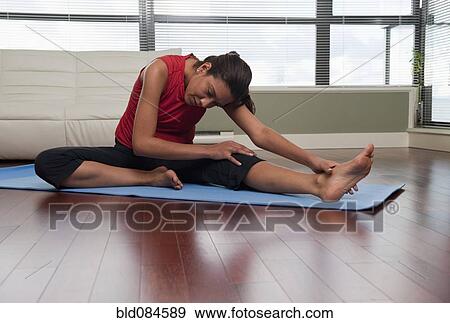 Stock Photo - Hispanic woman stretching on yoga mat. Fotosearch