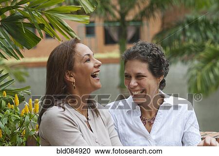 Stock Image - Hispanic women laughing together. Fotosearch
