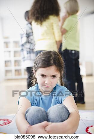 Stock Photo - Lonely girl ignoring friends playing. Fotosearch