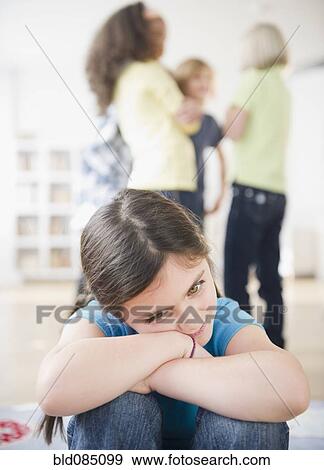 Lonely girl ignoring friends playing View Large Photo Image Stock Photo - Lonely girl ignoring friends playing. Fotosearch