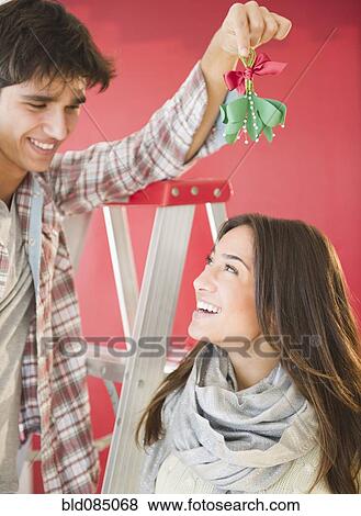 Stock Photo - Man holding mistletoe over wifeís head. Fotosearch
