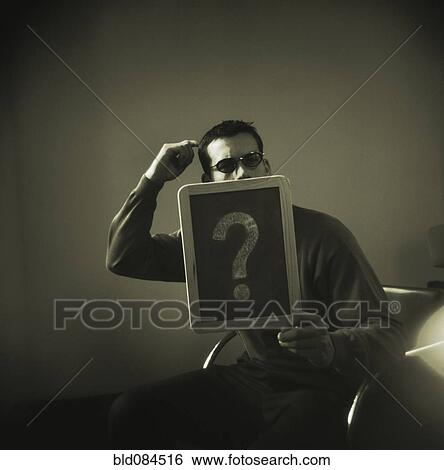 Stock Photograph - Man holding question mark on chalk board. Fotosearch