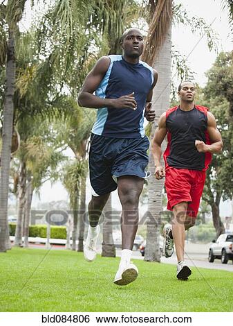 Stock Photograph - Men running in park together. Fotosearch