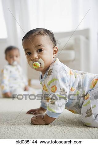 Picture - Mixed race baby crawling on floor. Fotosearch