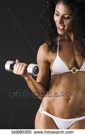 Mixed race female body builder doing biceps curls View Large Photo Image Stock Photography - Mixed race female body builder doing biceps curls. Fotosearch
