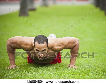 Picture - Mixed race man doing push-ups in park. Fotosearch