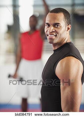 Stock Image - Mixed race man exercising in health club. Fotosearch