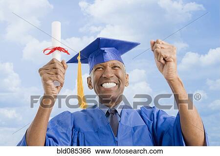 Stock Photograph - Mixed race man in graduation cap and gown holding diploma. Fotosearch