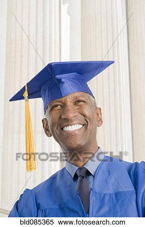 Stock Photography - Mixed race man in graduation cap and gown. Fotosearch