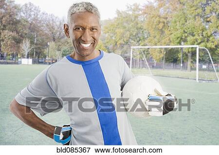 Mixed race man in soccer uniform holding ball View Large Photo Image Stock Photo - Mixed race man in soccer uniform holding ball. Fotosearch