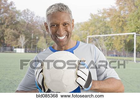 Mixed race man in soccer uniform holding ball View Large Photo Image Stock Photo - Mixed race man in soccer uniform holding ball. Fotosearch