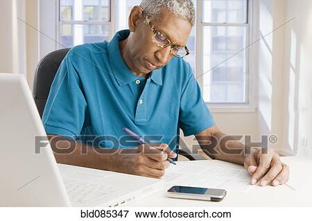 Stock Photo - Mixed race man paying bills online. Fotosearch