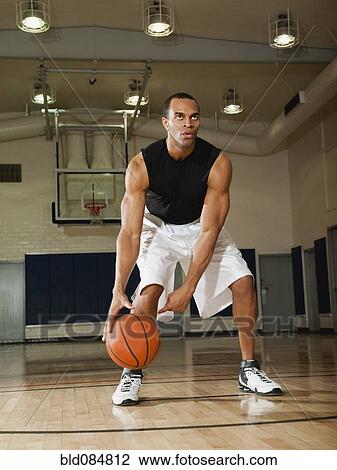 Stock Image - Mixed race man playing basketball on basketball court. Fotosearch