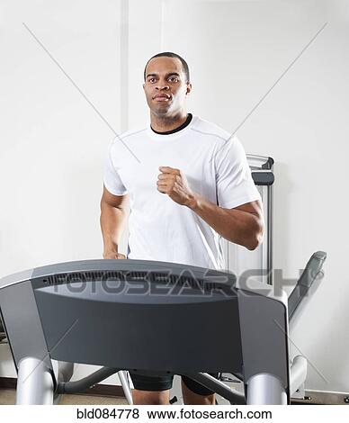 Stock Photo - Mixed race man running on treadmill. Fotosearch