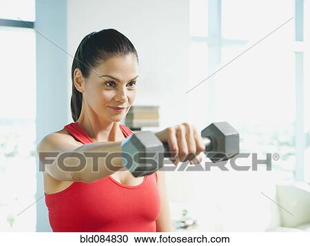 Stock Image - Mixed race woman exercising with dumbbells. Fotosearch