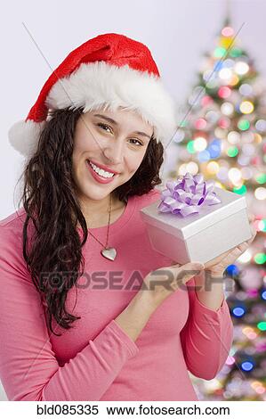Stock Photography - Mixed race woman holding Christmas gift. Fotosearch