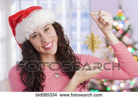 Picture - Mixed race woman holding Christmas ornament. Fotosearch
