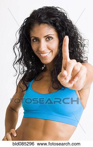 Stock Photograph - Mixed race woman in sportswear making Number One gesture. Fotosearch