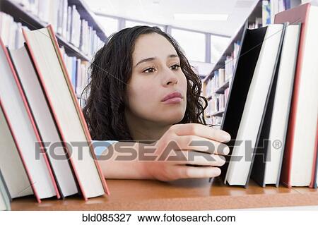 Stock Photo - Mixed race woman looking for book in library. Fotosearch