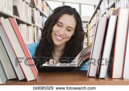 Stock Photo - Mixed race woman looking for book in library. Fotosearch