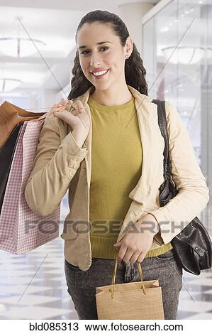 Stock Image - Mixed race woman shopping and carrying shopping bags. Fotosearch