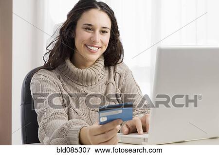 Stock Photo - Mixed race woman shopping online with credit card. Fotosearch