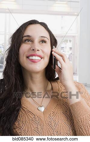Stock Image - Mixed race woman talking on cell phone. Fotosearch