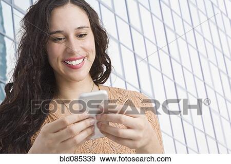 Stock Photo - Mixed race woman text messaging on cell phone. Fotosearch