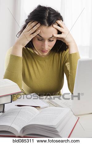 Mixed race woman with headache studying textbooks View Large Photo Image Stock Image - Mixed race woman with headache studying textbooks. Fotosearch