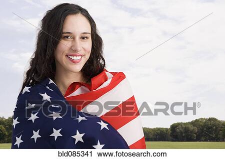 Stock Image - Mixed race woman wrapped in American flag. Fotosearch