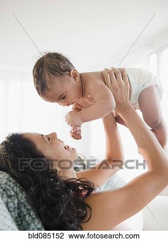 Stock Image - Mother lifting baby boy. Fotosearch