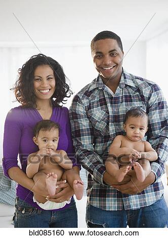Stock Image - Parents holding twin baby boys. Fotosearch