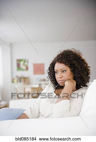 Picture - Sad African American woman sitting on sofa. Fotosearch