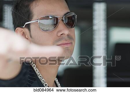 Picture - Serious Hispanic man wearing sunglasses. Fotosearch