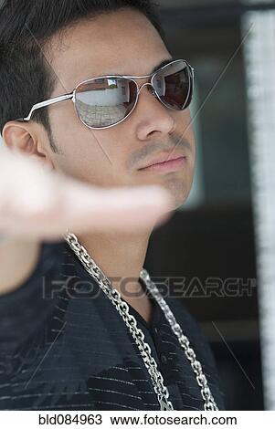 Stock Image - Serious Hispanic man wearing sunglasses. Fotosearch