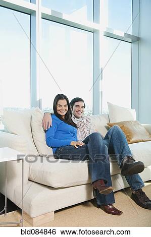 Stock Photograph - Smiling couple sitting on sofa. Fotosearch