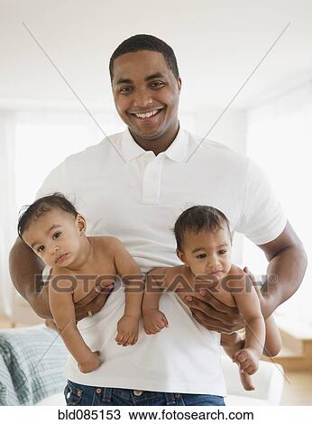 Smiling father holding twin baby boys View Large Photo Image Stock Image - Smiling father holding twin baby boys. Fotosearch