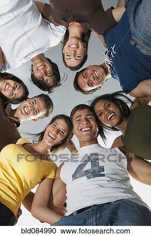 Stock Image - Smiling friends in huddle together. Fotosearch
