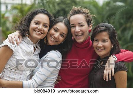 Stock Photo - Smiling Hispanic friends hugging. Fotosearch