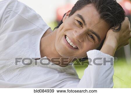 Smiling Hispanic man laying on ground View Large Photo Image Stock Photo - Smiling Hispanic man laying on ground. Fotosearch