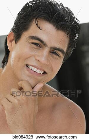 Stock Photo - Smiling Hispanic man with hand on chin. Fotosearch