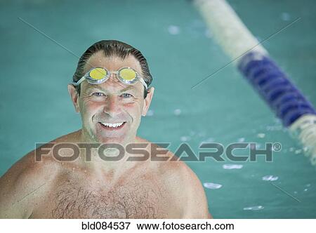 Stock Photo - Smiling man with goggles in swimming pool. Fotosearch